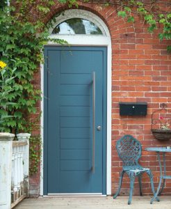 Modern teal aluminium front door from Smarts on a classic brick house, featuring a long pull handle and transom window for a stylish entrance.